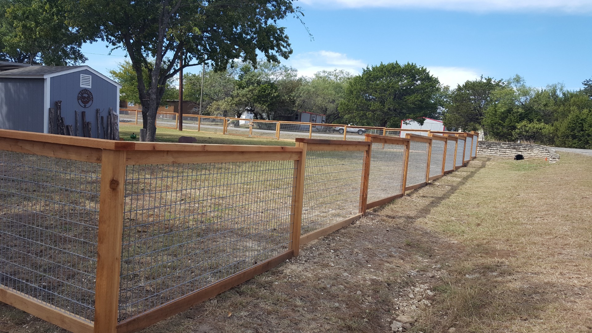 Wire livestock fence along a wood post line enclosing an open pasture near Granbury, TX