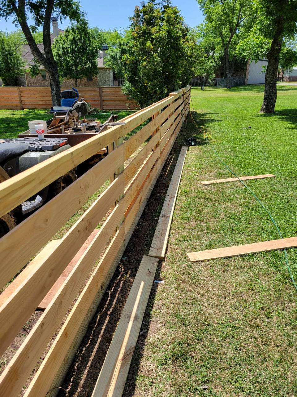 All Around Fencing crew building a wood fence with tools and a trailer on site