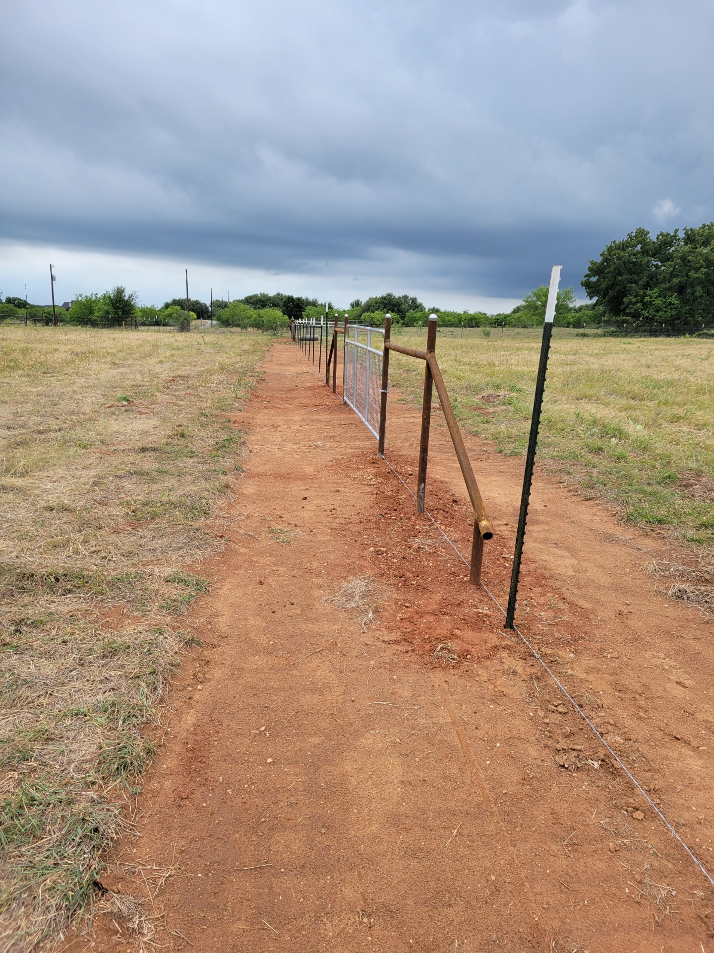 Wire and pipe field fence with a gate on a rural Hood County property
