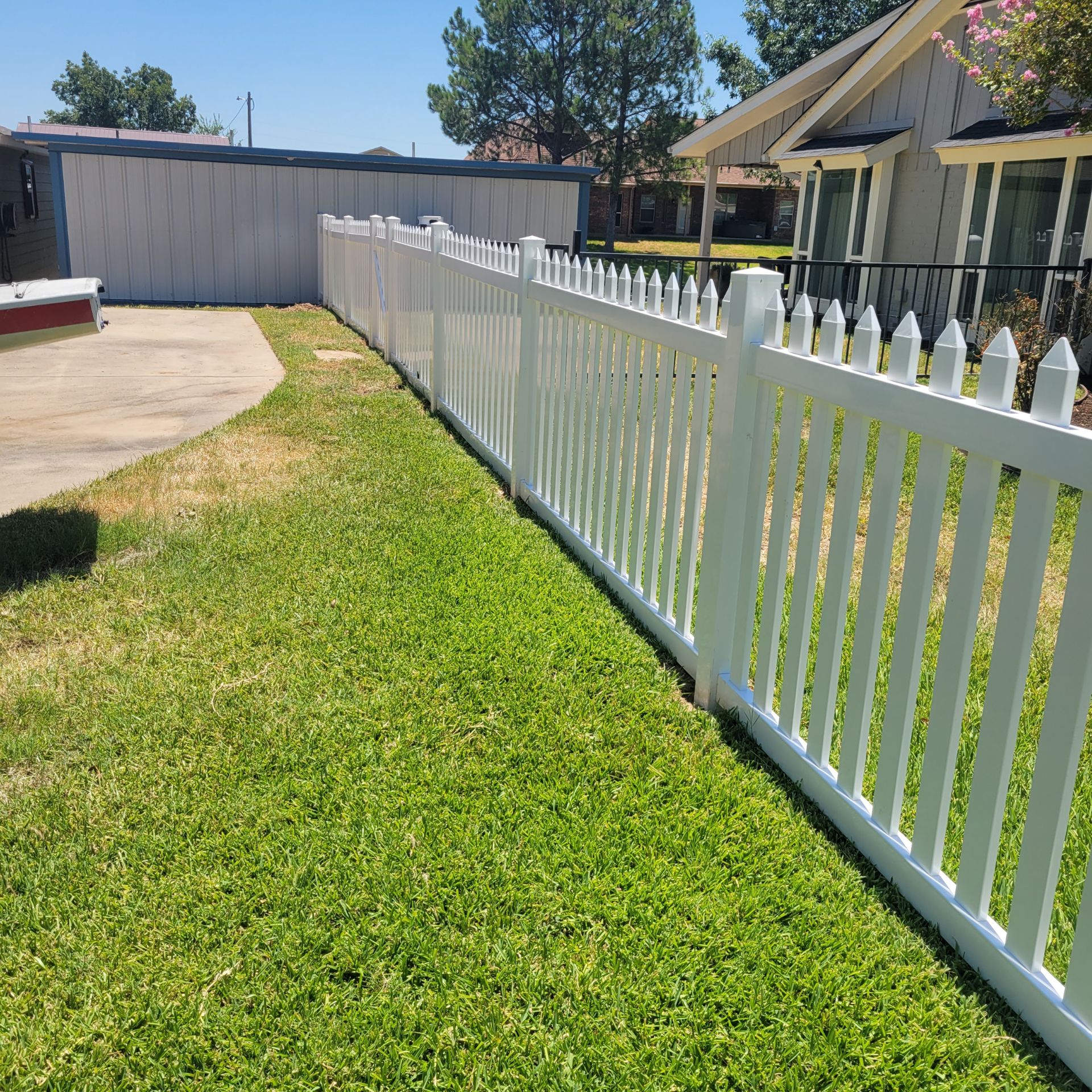 White vinyl picket fence installed along a residential side yard near Granbury, TX