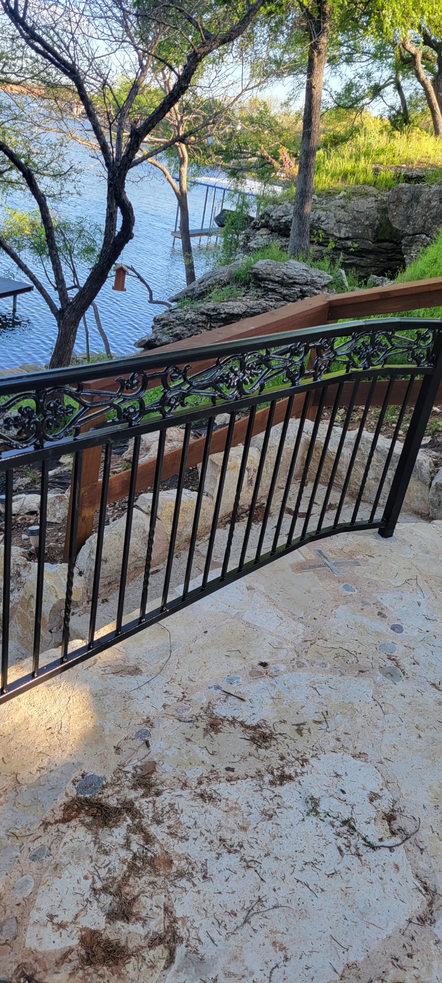 Black scrolled ornamental iron railing along stone steps overlooking Lake Granbury